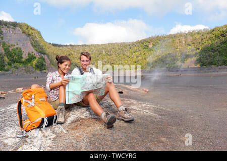 Couple hiking on volcano on Hawaii looking at map. Happy young man and woman relaxing taking break in beautiful volcanic landscape nature on Big Island in Hawaii Volcanoes National Park, USA. Stock Photo