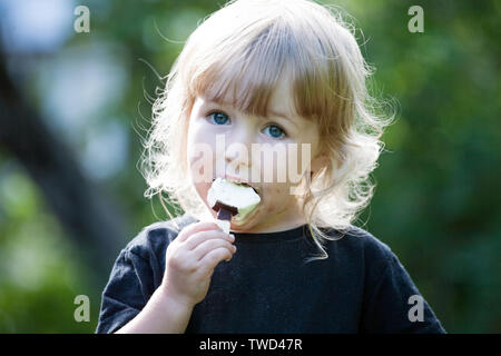 little girl with chocolate popsicle ice cream in the hand closeup view Stock Photo