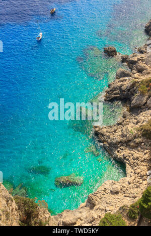Mediterranean sea with alone boats on blue water, Capri island, Italy.