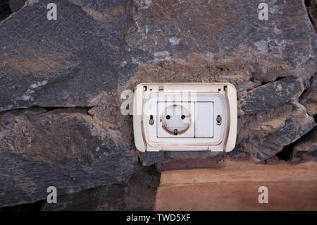 Image of an aged plug placed in a rustic stone wall with space to the left to add some graphic element Stock Photo