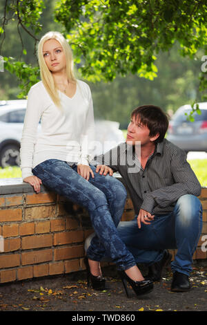 Young couple in conflict on city street Stylish trendy man and woman in long sleeve shirts and blue jeans Stock Photo