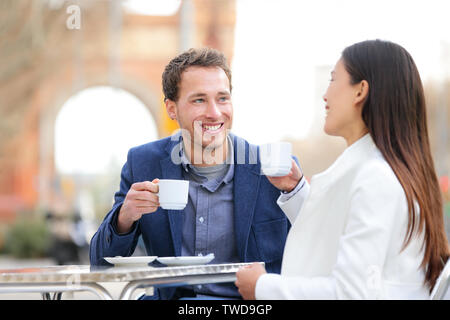 Couple dating drinking coffee at sidewalk cafe outdoors on date. Young beautiful professionals talking enjoying espresso laughing having in Barcelona, Spain near Arc de Triomf on Passeig de Sant Joan. Stock Photo