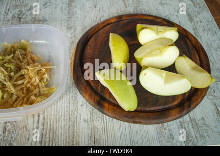Sliced yellow apple on a cutting board and grated apple on a light wooden table, copyspace Stock Photo