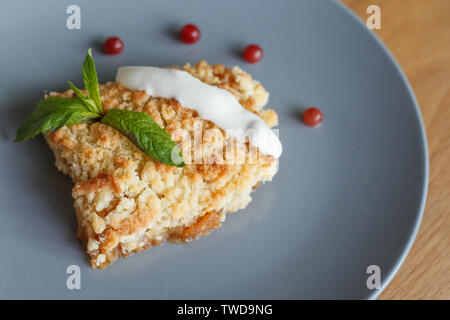 Served slice of freshly baked homemade apple crisp pie with cream and berries on a gray plate, copyspace Stock Photo
