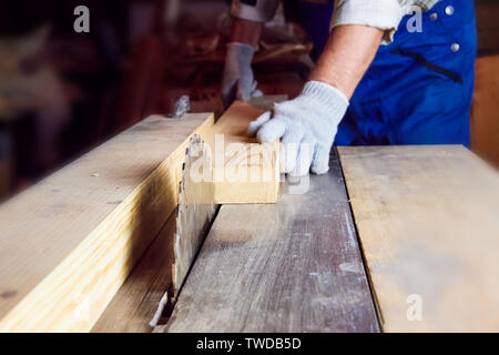 Carpenter works on woodworking machines in the carpentry workshop. A man works with a tree Stock Photo