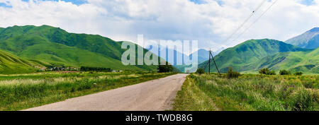 Panorama of a mountain valley in the summer. Fabulous view of the mountain range and the road extending into the distance of the ridge, amazing nature Stock Photo