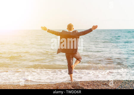 Happy businessman doing yoga at the beach Stock Photo