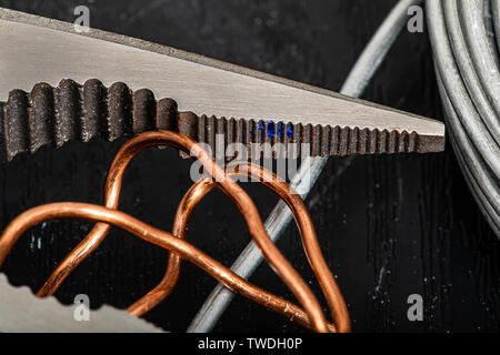 Needle nose pliers in a macro shot with tight focus on the plier teeth.  A typical group of tools and materials to find in any home tool kit Stock Photo