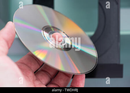 Man hand holding a CD above a CD player close-up view Stock Photo