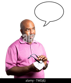 African American man in a a purple shirt cleaning the lenses of a pair of eyeglasses with a microfiber cloth on white background. Speech think bubble Stock Photo