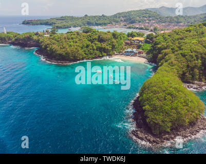 Sea bay with turquoise water and a small white beach. Beautiful lagoon and volcanic island covered with dense forest, view from above Stock Photo