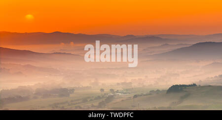 Tuscany hilly landscape scene with early morning haze over village countryside Stock Photo