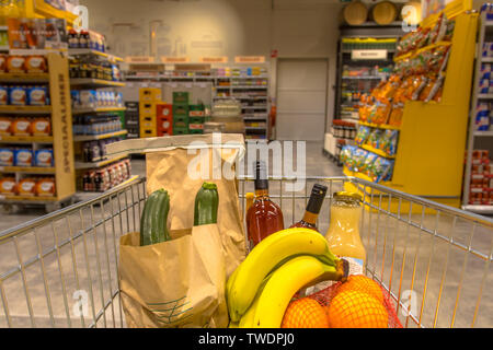 Grocery cart in supermarket filled with food products seen from the customers point of view Stock Photo