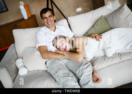 Happy pregnant beautiful blonde is lying on the lap of her beloved husband Stock Photo