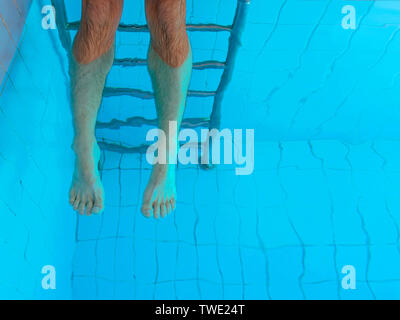adult cuacasian man's legs underwater in swimming pool. Summer. Vacation and sport concept. Stock Photo