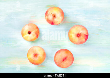 Vibrant organic flat saturn peaches, shot from the top on a teal background, forming a circular frame with copy space Stock Photo