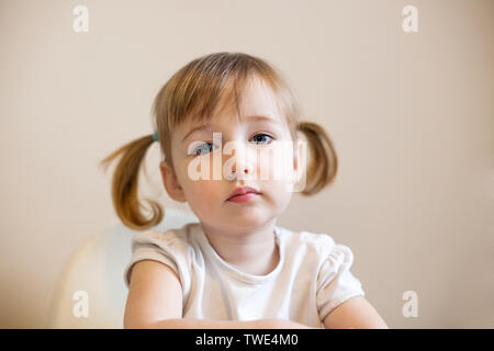 little kid Caucasian girl face closeup cute portrait with pigtails on plain background