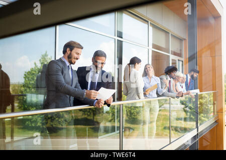 Group of modern business people chatting during coffee break standing in office building Stock Photo