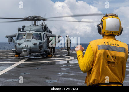 190615-N-HD110-0106  SOUTH CHINA SEA (June 15, 2019) Sailors observe an MH-60 Sea Hawk helicopter, attached to Helicopter Sea Combat Squadron (HSC) 21, as it lands on the flight deck of the Harpers Ferry-class amphibious dock landing ship USS Harpers Ferry (LSD 49). Harpers Ferry is part of the Boxer Amphibious Ready Group (ARG) and 11th Marine Expeditionary Unit (MEU) team and is deployed to the U.S. 7th Fleet area of operations to support regional stability, reassure partners and allies, and maintain a presence postured to respond to any crisis ranging from humanitarian assistance to conting Stock Photo