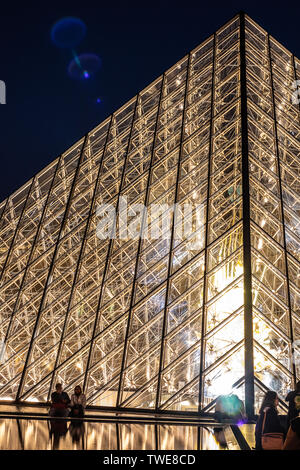 Paris, France, October 04, 2018: The Louvre Palace and the pyramid (by night) as entrance inside Louvre Museum, tourists sightseeing, taking pictures Stock Photo