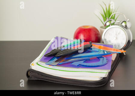 soon to school, school notebooks and stationery, alarm clock and Apple on the table, the concept of the beginning of the school year Stock Photo