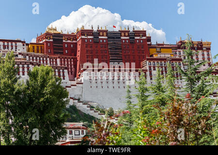 View on main part of Potala Palace (Lhasa, Tibet) with blue sky & a big cloud in the background. Green trees on the left & right complete the photo. Stock Photo