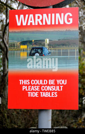 A warning sign just before the causeway connecting Lindisfarne Holy Island (a tidal island) to the mainland in Northumberland, Britain.  It is to wa Stock Photo