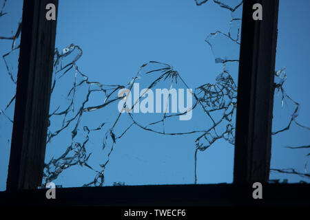 cracked and broken window glass punched by a pistol bullet Stock Photo