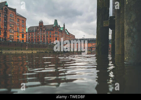 low angle view of channel and historic warehouses in the Speicherstadt district of Hamburg against clouded sky Stock Photo