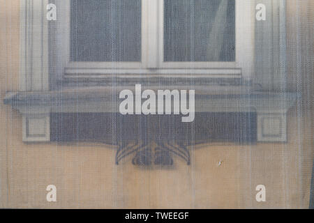 Window of the old house on the yellow wall behind the building grid in Riga Stock Photo