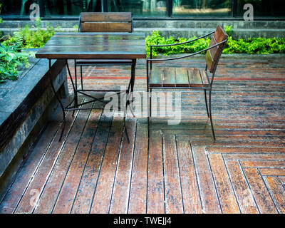 Wooden chairs and wooden table on wooden floor near the green garden with copy space. Stock Photo