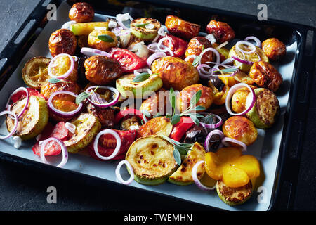 close-up of freshly roasted in an oven hot vegetables on a baking pan on a grey concrete table, view from above Stock Photo