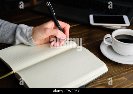 Woman writing by left hand in notebook. Left hander day concept. Working place of lefty Stock Photo
