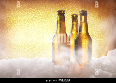 Three full beer bottles on crushed ice and golden background . Horizontal composition. Front view. Stock Photo