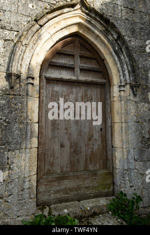 closed ancient wooden door in an arched stone doorway Stock Photo