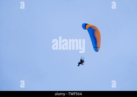 A motorised paraglider against a blue sky. Stock Photo