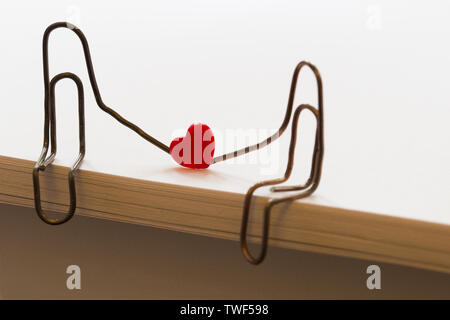 paper clips with heart symbolizing a person sitting on a stack of white paper. love concept Stock Photo