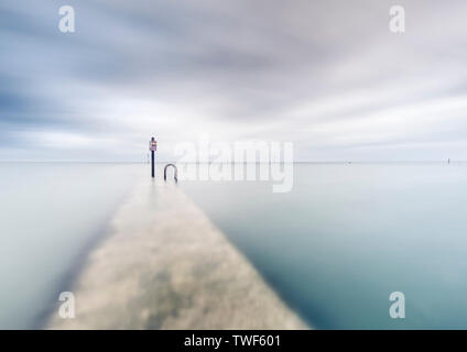 On the wall of the Margate tidal pool at high tide in Kent. Stock Photo