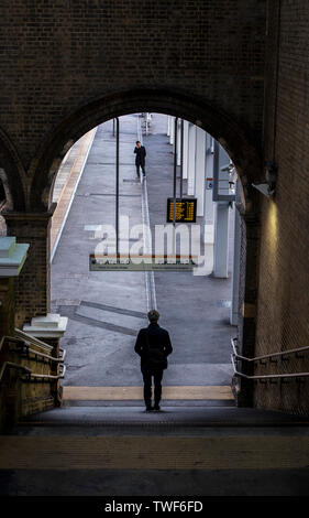 Elevated view of man walking down slope towards train platform in Crystal Palace in London. Stock Photo