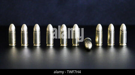 Close up of 9 mm golden pistol bullets ammo on background. Special force units. Stock Photo