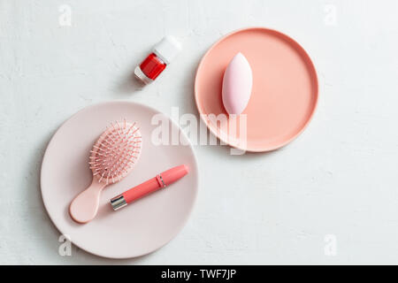 Makeup products on pink plate on white background Stock Photo