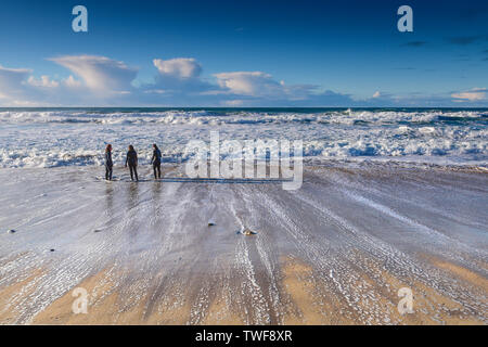 People in wetsuits standing on the shoreline at Fistral Beach in Newquay in Cornwall. Stock Photo