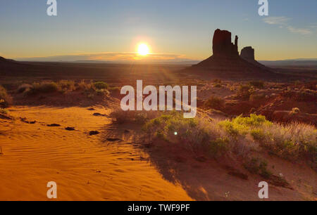 Monument Valley Navajo Tribal Park in the Arizona-Utah border USA, at sunrise. Sun rising behind the red rocks, clear sky background Stock Photo