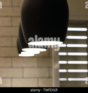 Bar lights in the form of black wine glasses on the background of white brick wall and the slit in blinds. Design for studio, bar and restaurant. Stock Photo