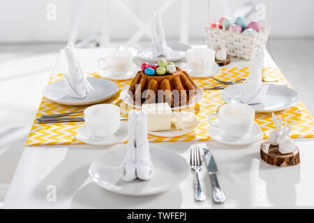 Easter cake, painted eggs and crockery on table in kitchen Stock Photo