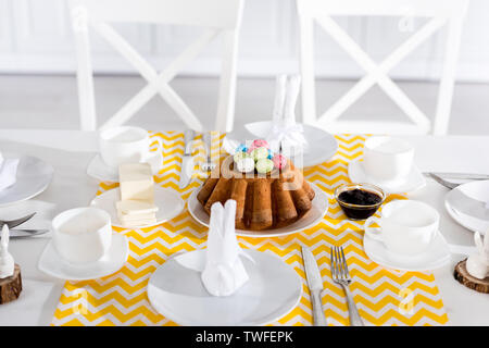 Easter cake with painted eggs and crockery on table Stock Photo