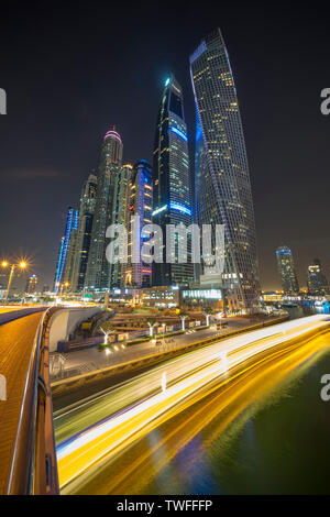 The light trails of a dinner cruise stream past in the Dubai Marina. Stock Photo