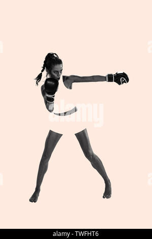 Young active beautiful woman full of energy with the black boxing gloves training and practicing at the studio. Creative collage. Fitness, boxing, female strenght, sport, motion and movement concept. Stock Photo