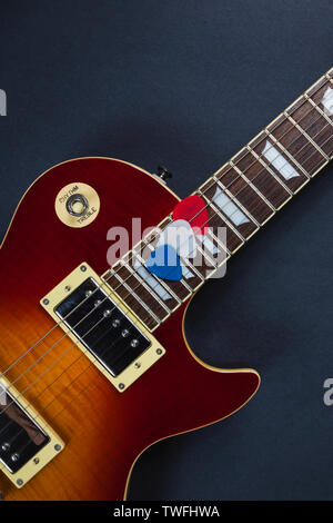 Les Paul style electric guitar with red, white and blue picks. The colors make the picture patriotic for the 4th of July. The guitar has a cherry sunb Stock Photo
