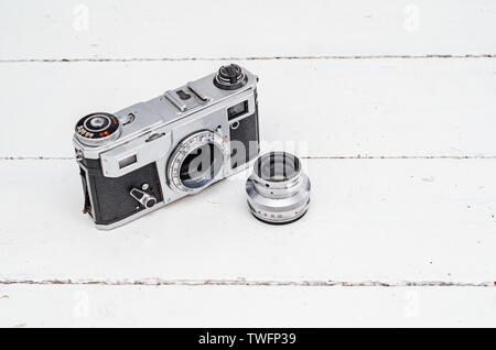 Film camera on white boards with a detached lens. Stock Photo